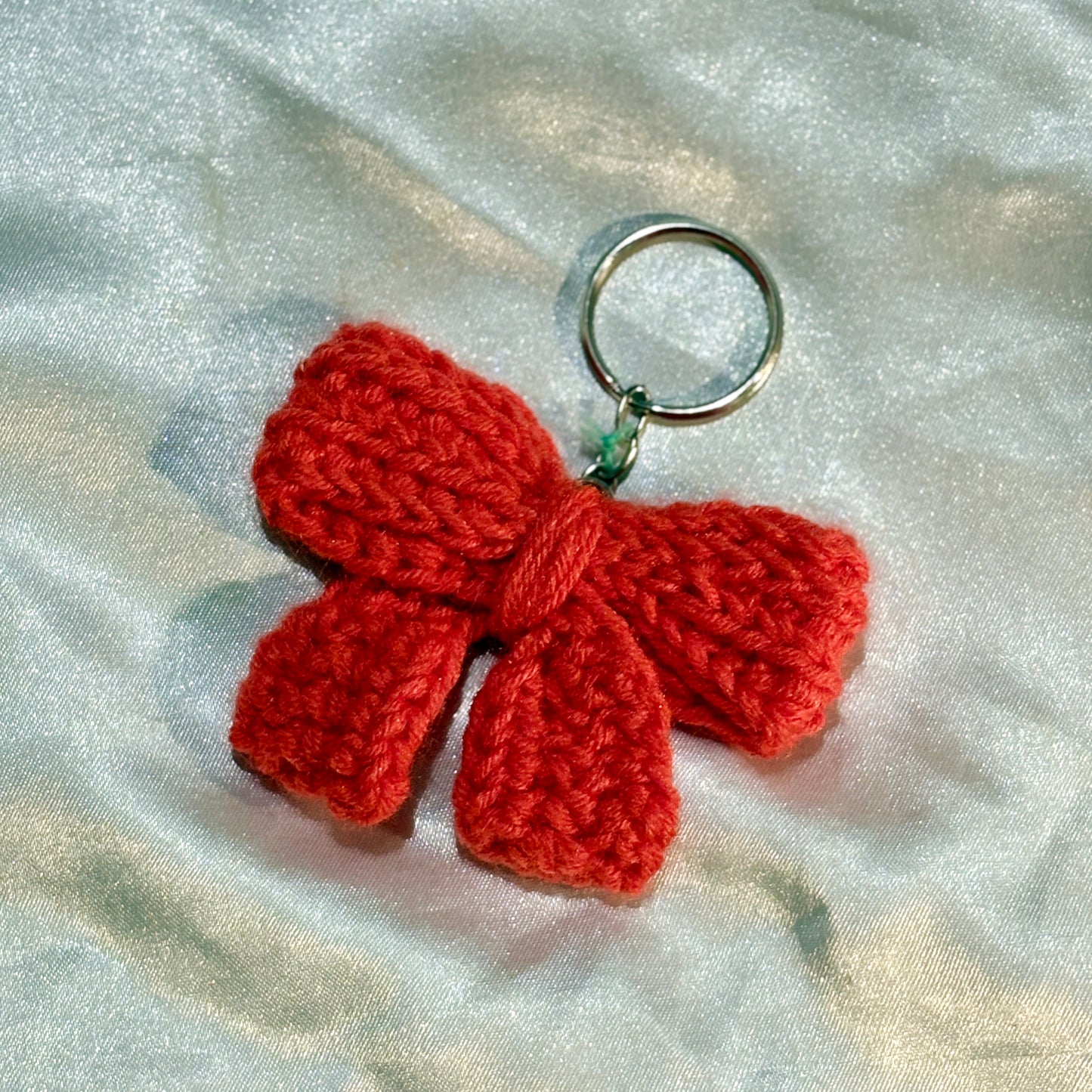 Red bow keychain on a silver satin background