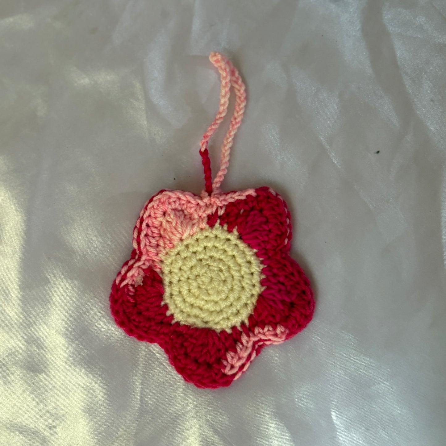Crocheted flower pouch with red, pink, and yellow colors on a light fabric background