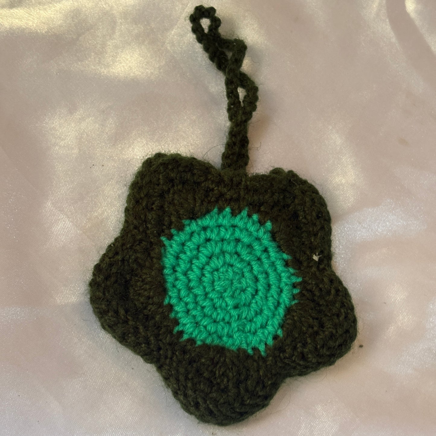 Crocheted green and black pouch on a white background