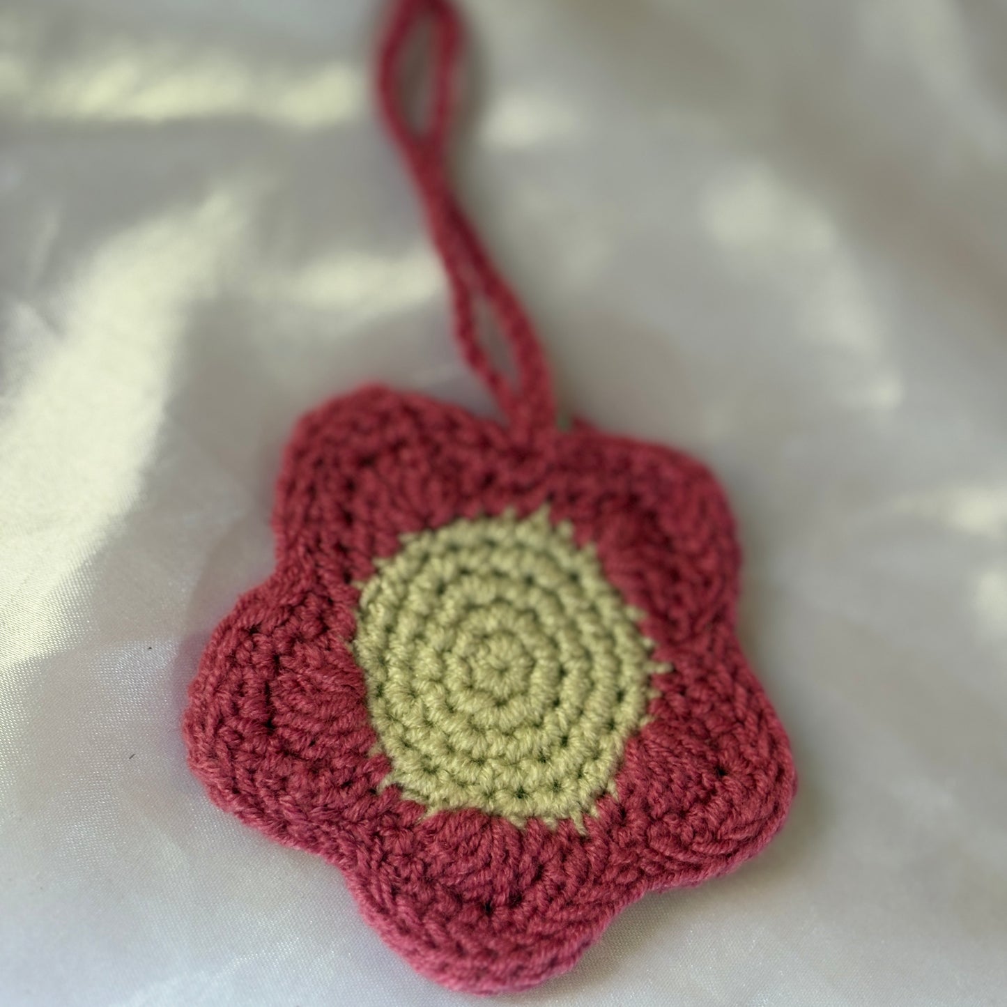 Crocheted flower pouch with red outer petals and yellow center on a white background