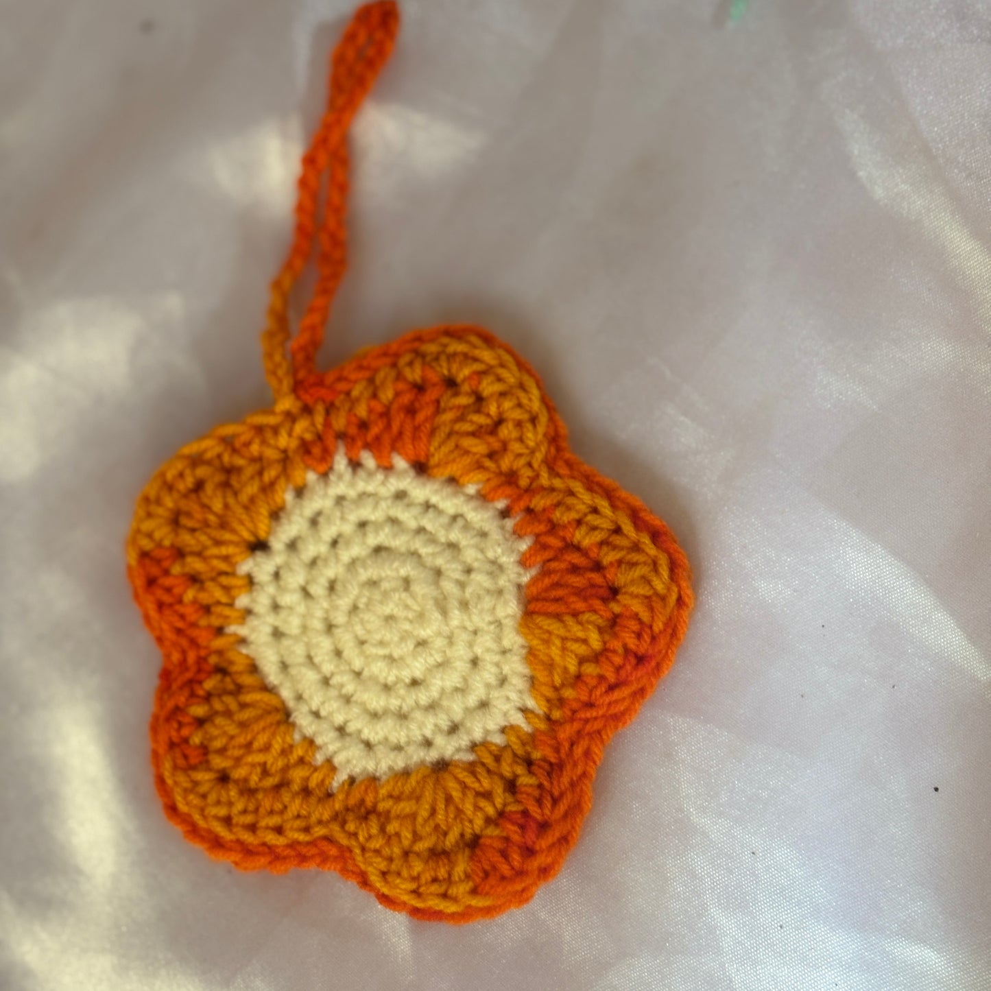 Crocheted flower pouch with orange and beige colors on a white background