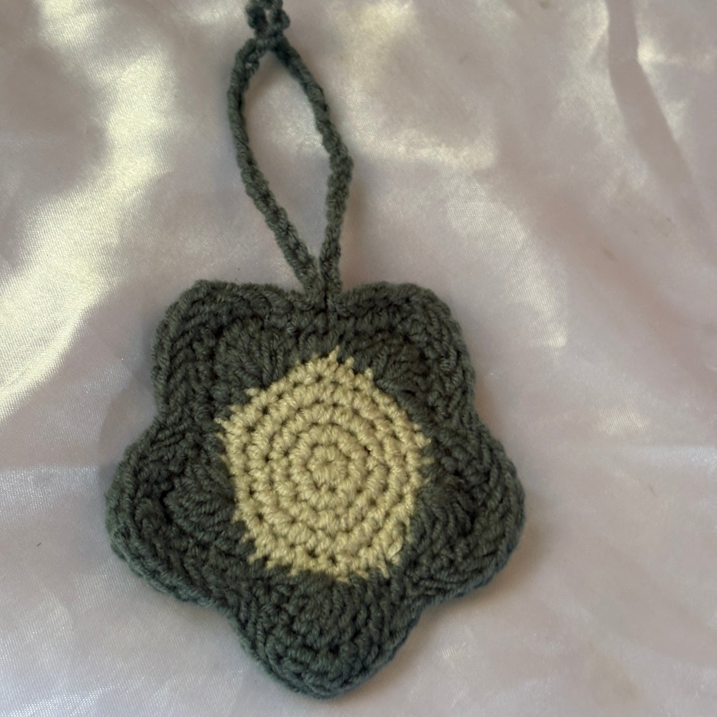 Crocheted heart-shaped pouch with a yellow center on a light pink background