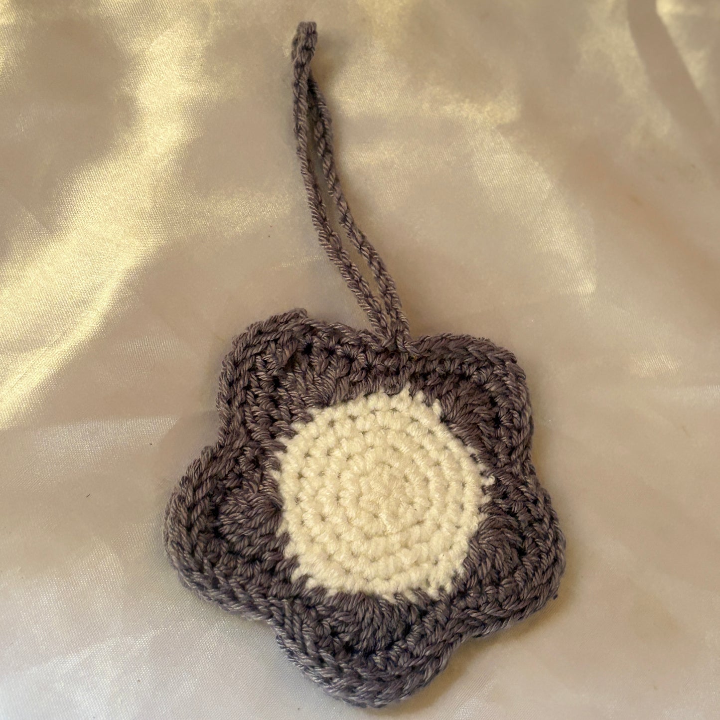Crocheted flower-shaped pouch with a white center on a beige fabric background