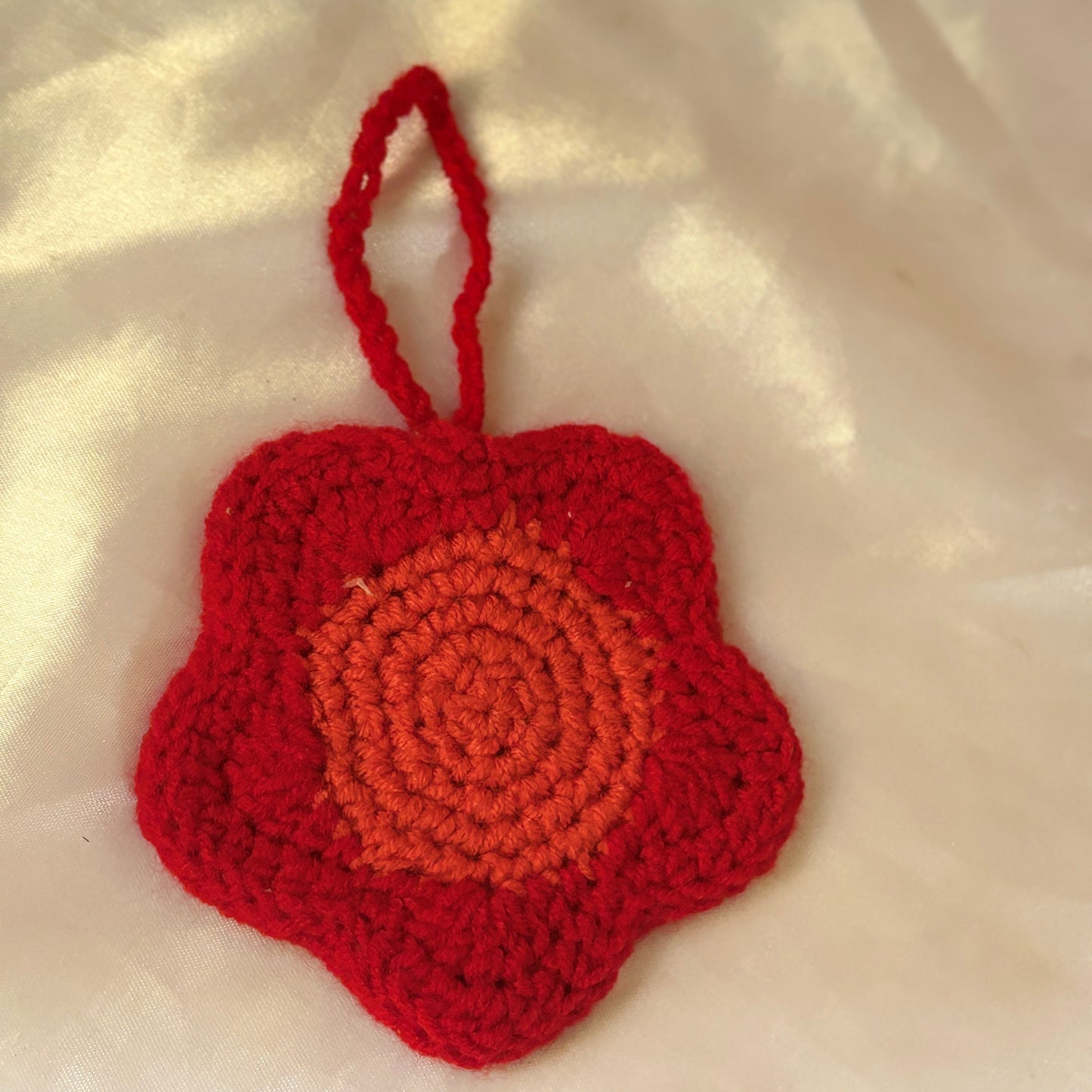 Red crocheted heart-shaped pouch on a beige fabric background