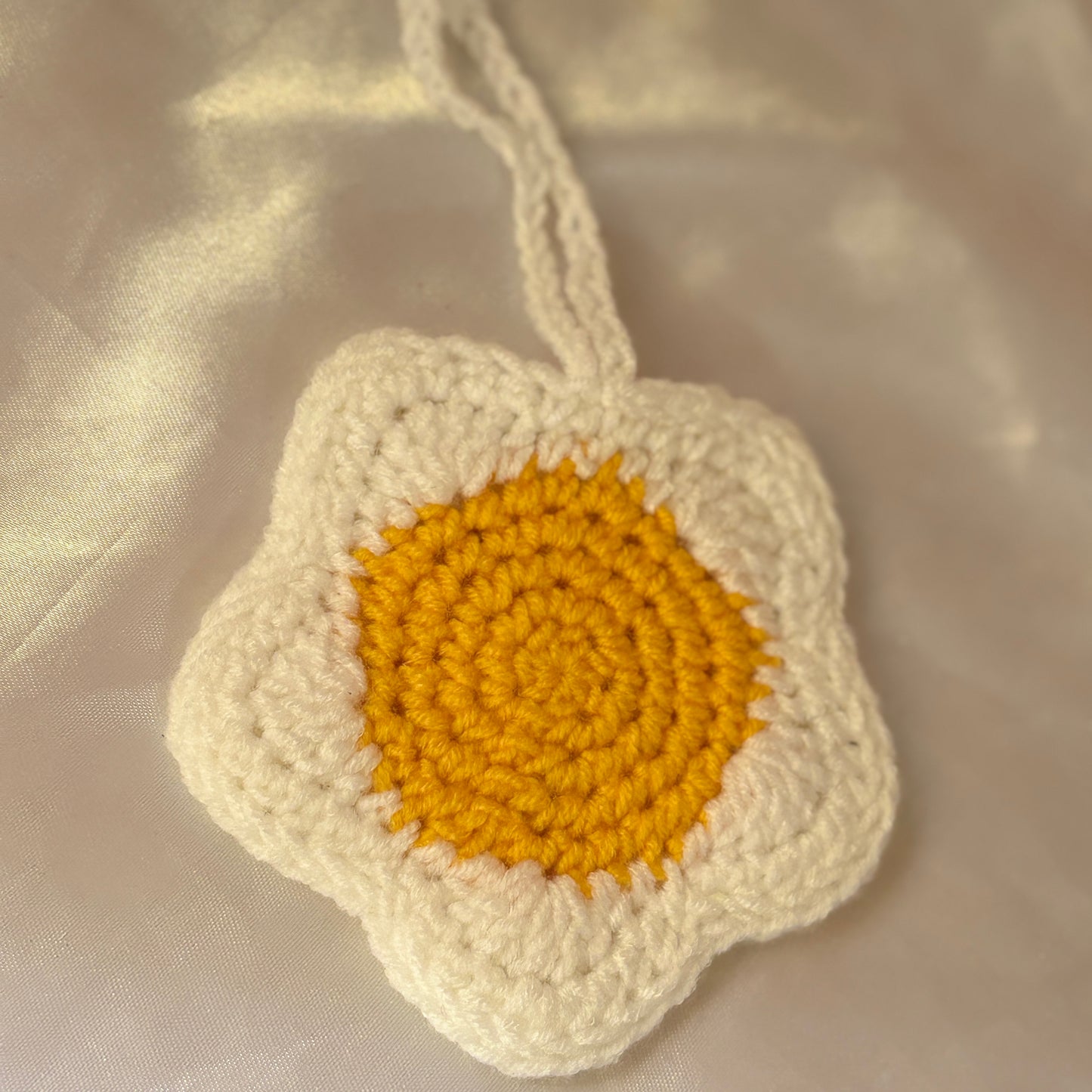 Crocheted flower pouchwith a yellow center on a beige fabric background