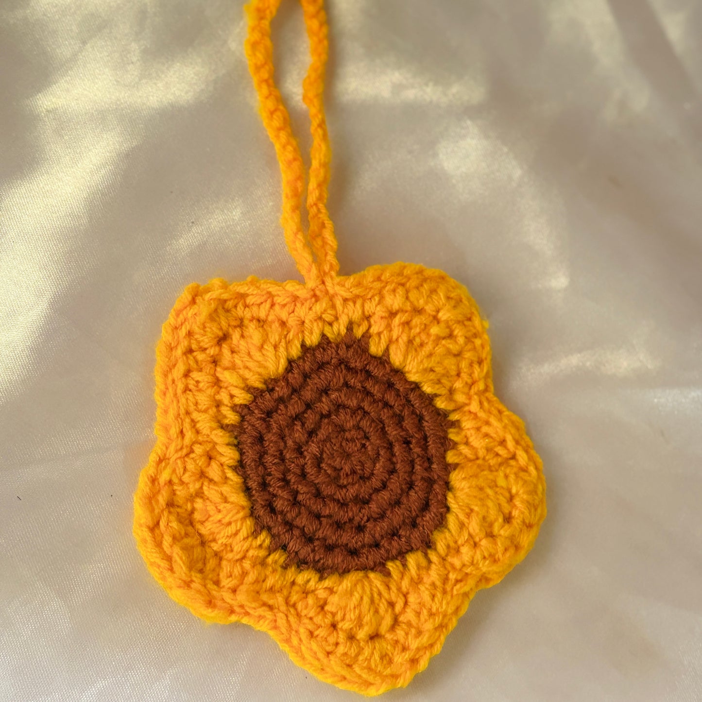 Crocheted sunflower pouch on a light fabric background