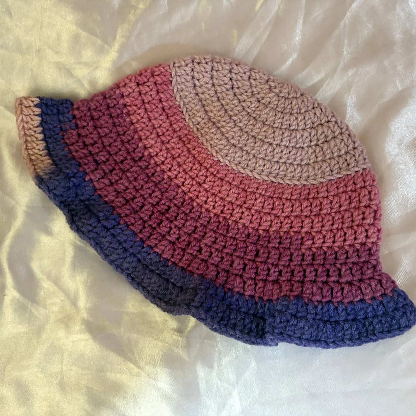 Crocheted hat with gradient colors on a white fabric background