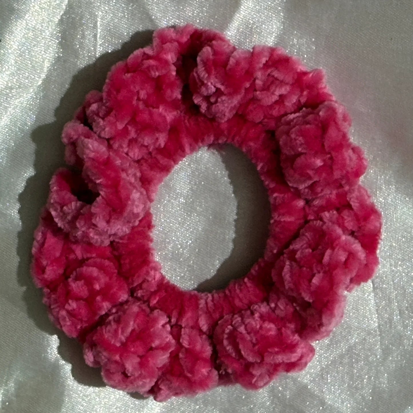Pink textured scrunchie on a light gray background