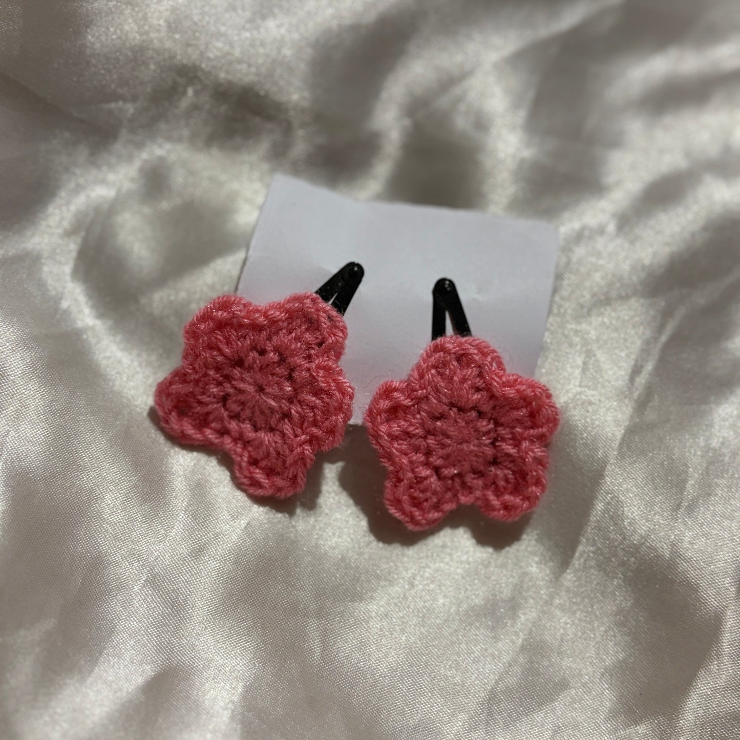 pink crocheted black clips on a white fabric background