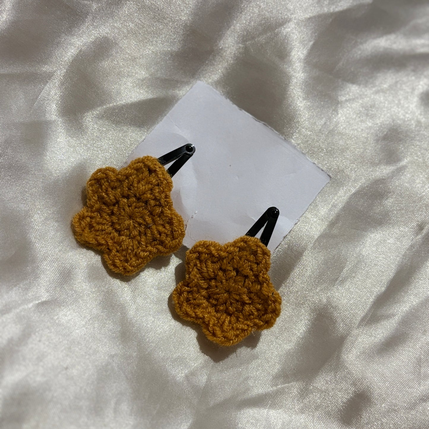 Two brown crochet hair clips on a white fabric background