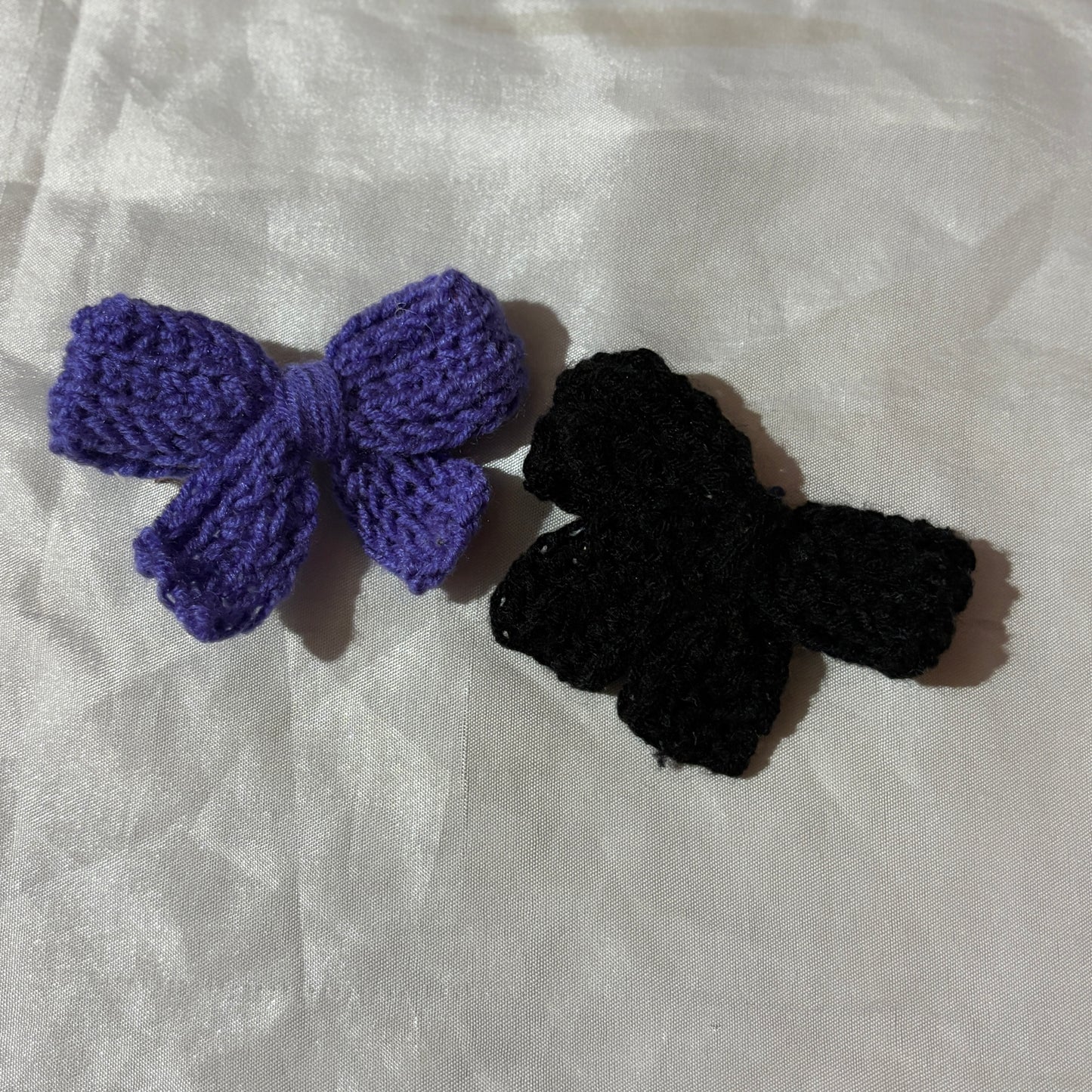 Purple and black crochet hair accessories on a white fabric background