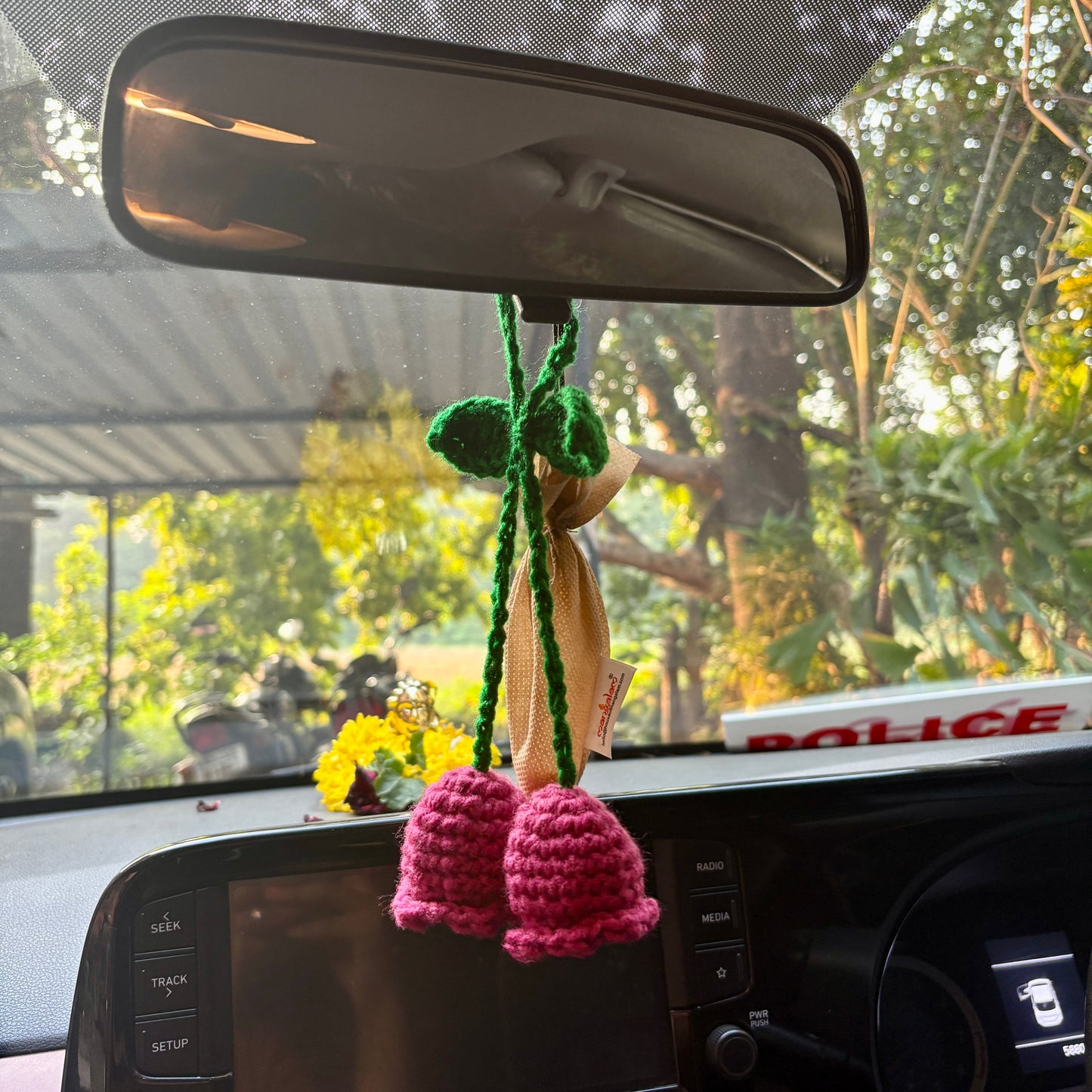 Crocheted flower decoration hanging from a car's rearview mirror