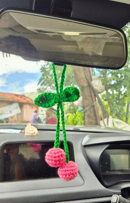 Car interior with a green and pink hanging ornament on the rearview mirror