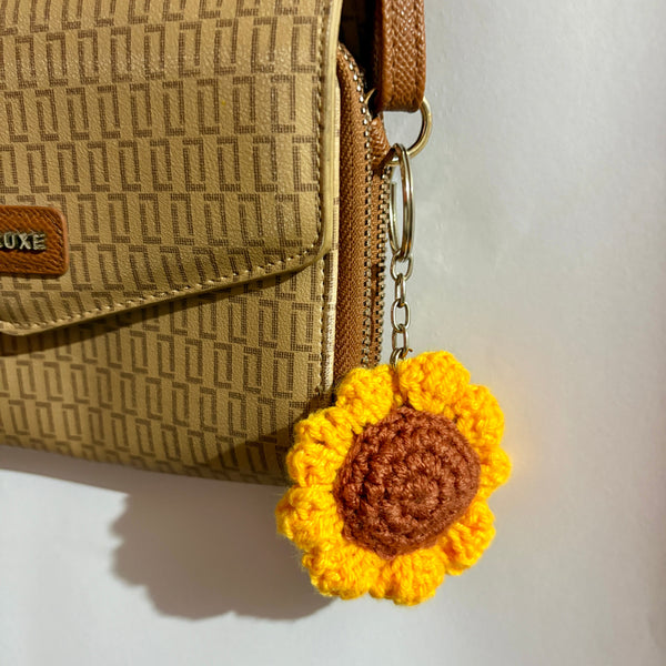 Beige handbag with a yellow sunflower keychain on a white background