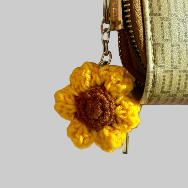 textured wallet with a yellow flower keychain on a light pink surface