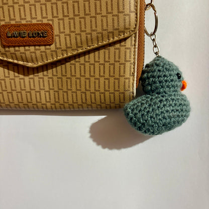 Brown textured wallet with a grey duck crocheted keychain on a white background
