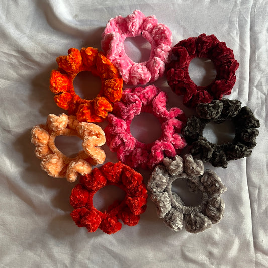 Set of colorful crocheted scrunchies on a white fabric background