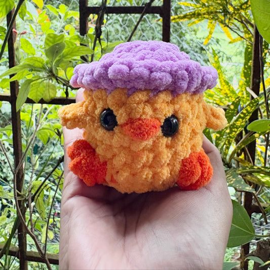 Plush toy resembling a character with a purple hat held in front of a natural background