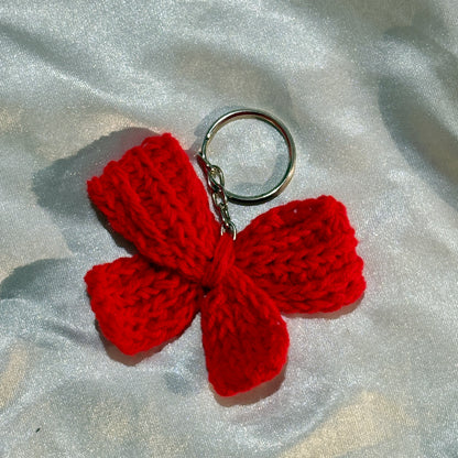 Red crochet bow keychain on a silver fabric background