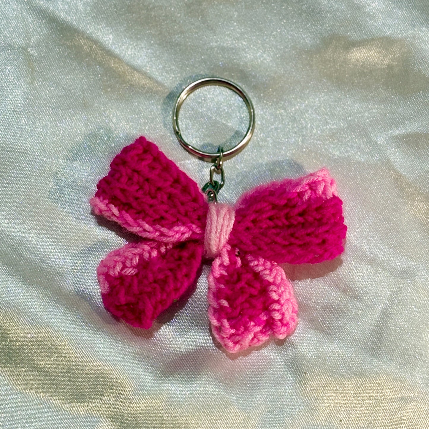 Pink bow keychain on a silver satin background