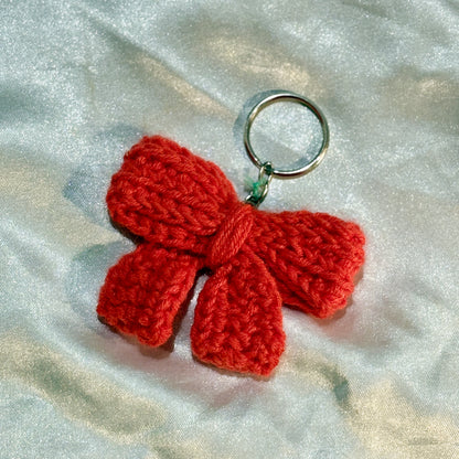 Red bow keychain on a silver satin background