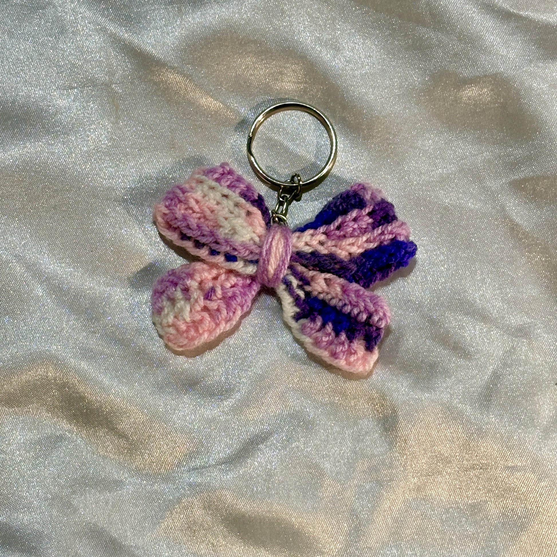 Purple bow keychain on a silver satin background