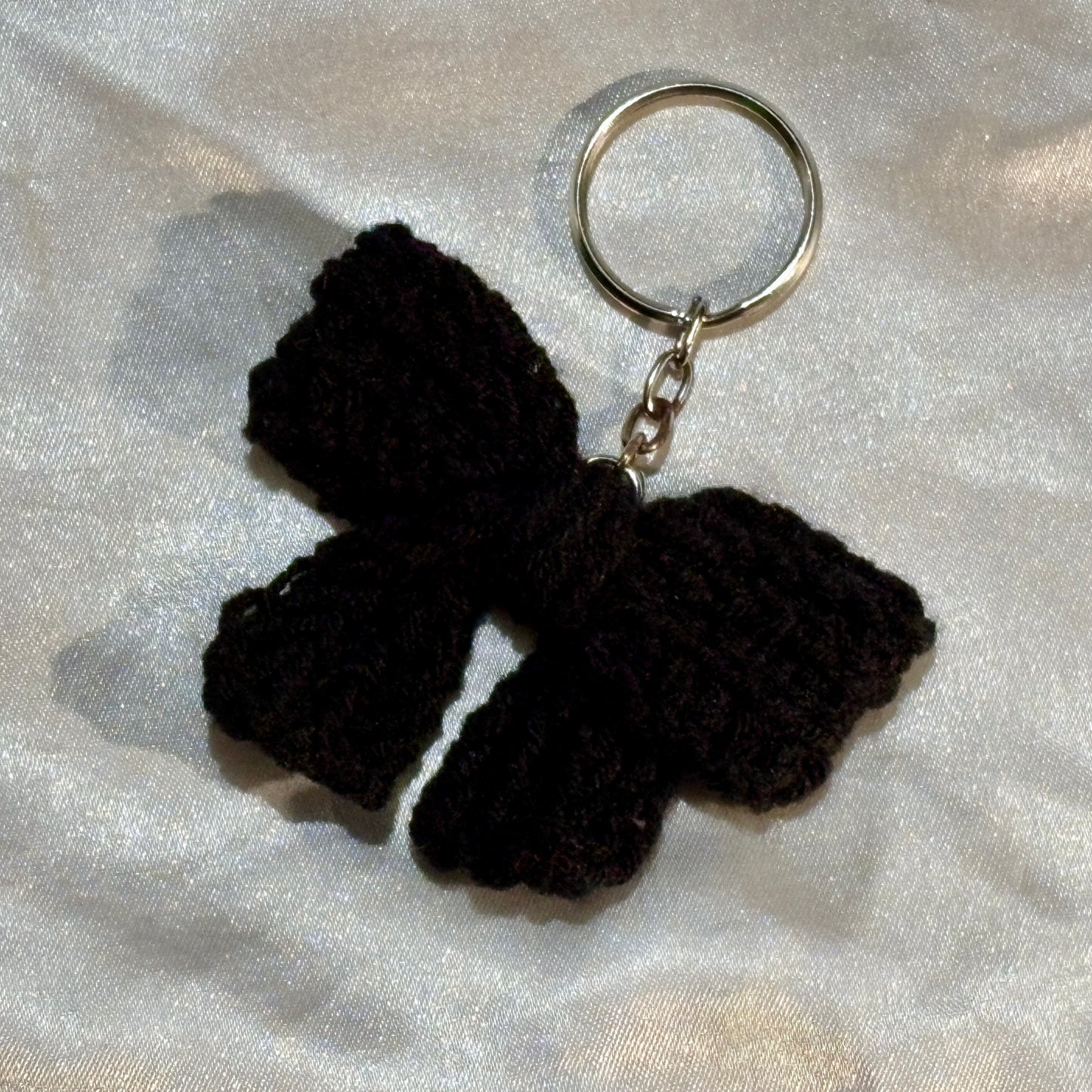 Black bow keychain on a silver satin background