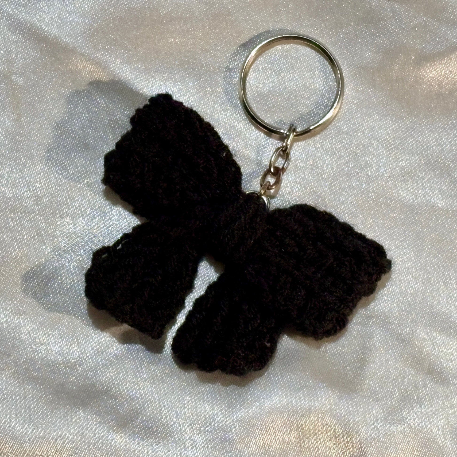 Black bow keychain on a silver satin background