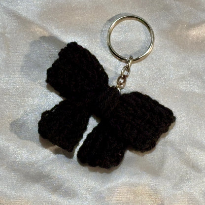 Black bow keychain on a silver satin background