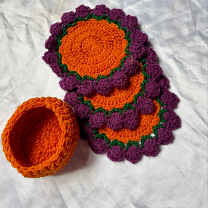 Set of purple and orange crocheted coasters on a white surface