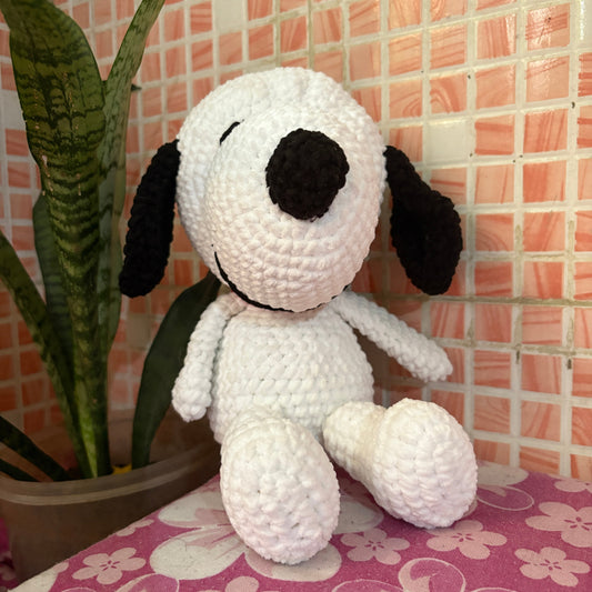 White and black dog-shaped plush toy on a pink floral background
