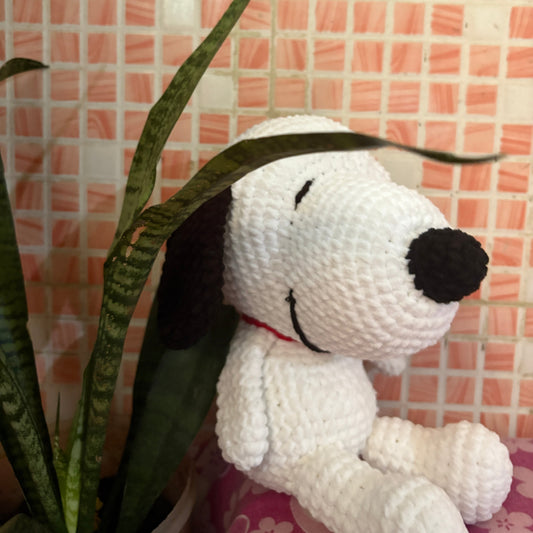 Crocheted dog toy with a black nose on a pink tiled wall background