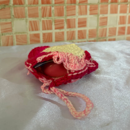 crochet pouch with a earphones and cash on a textured surface with a tiled wall background