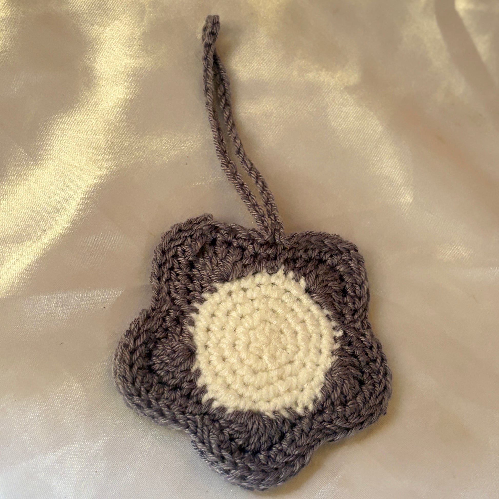 Crocheted flower-shaped pouch with a white center on a beige fabric background