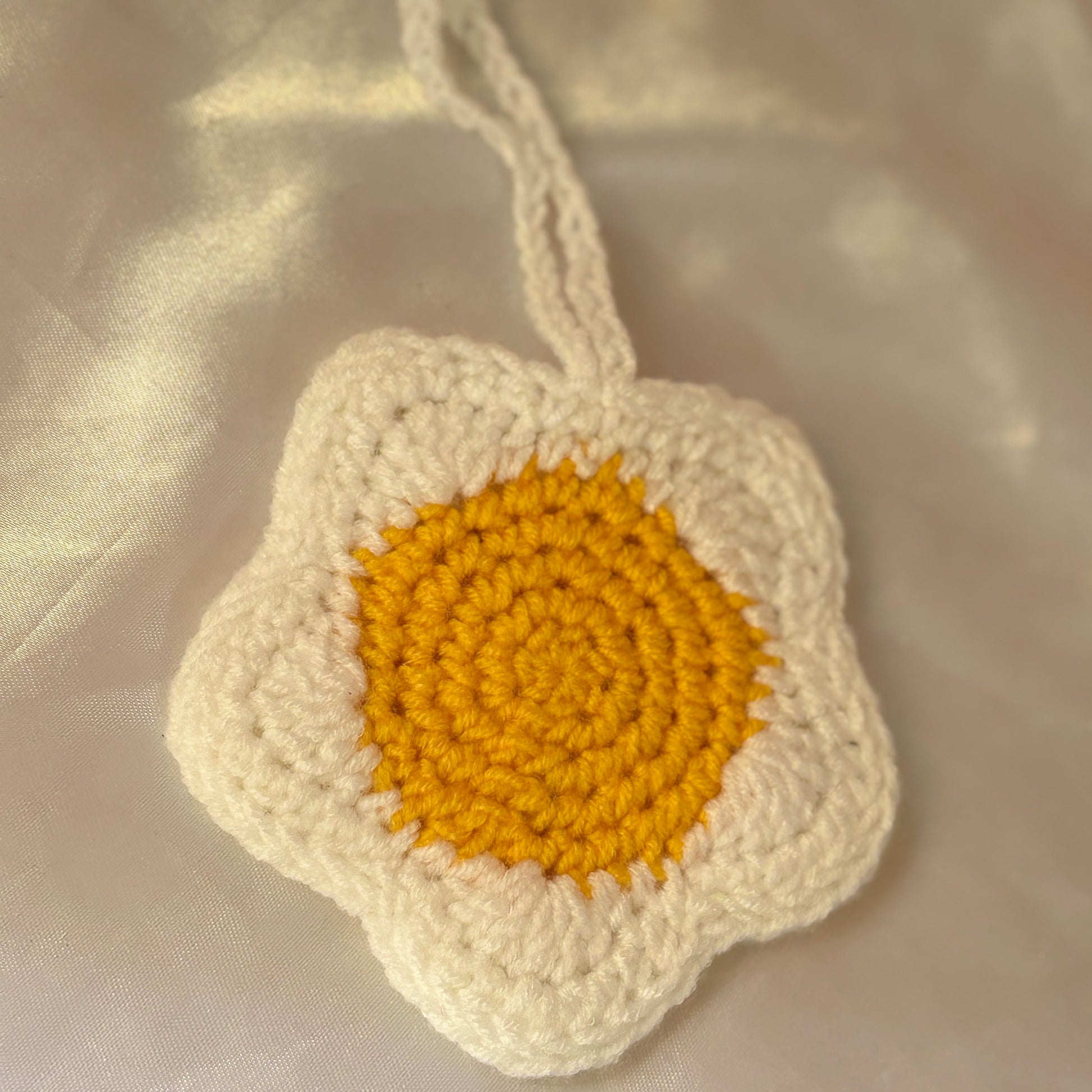 Crocheted flower pouchwith a yellow center on a beige fabric background