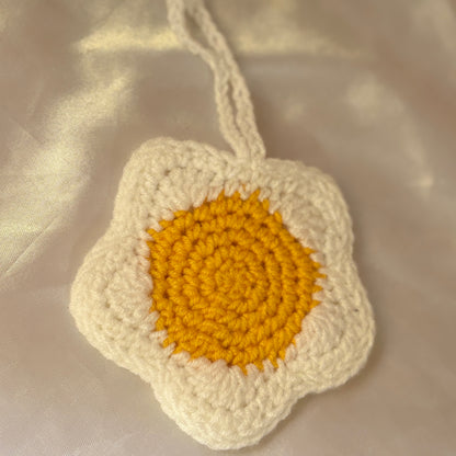Crocheted flower pouchwith a yellow center on a beige fabric background