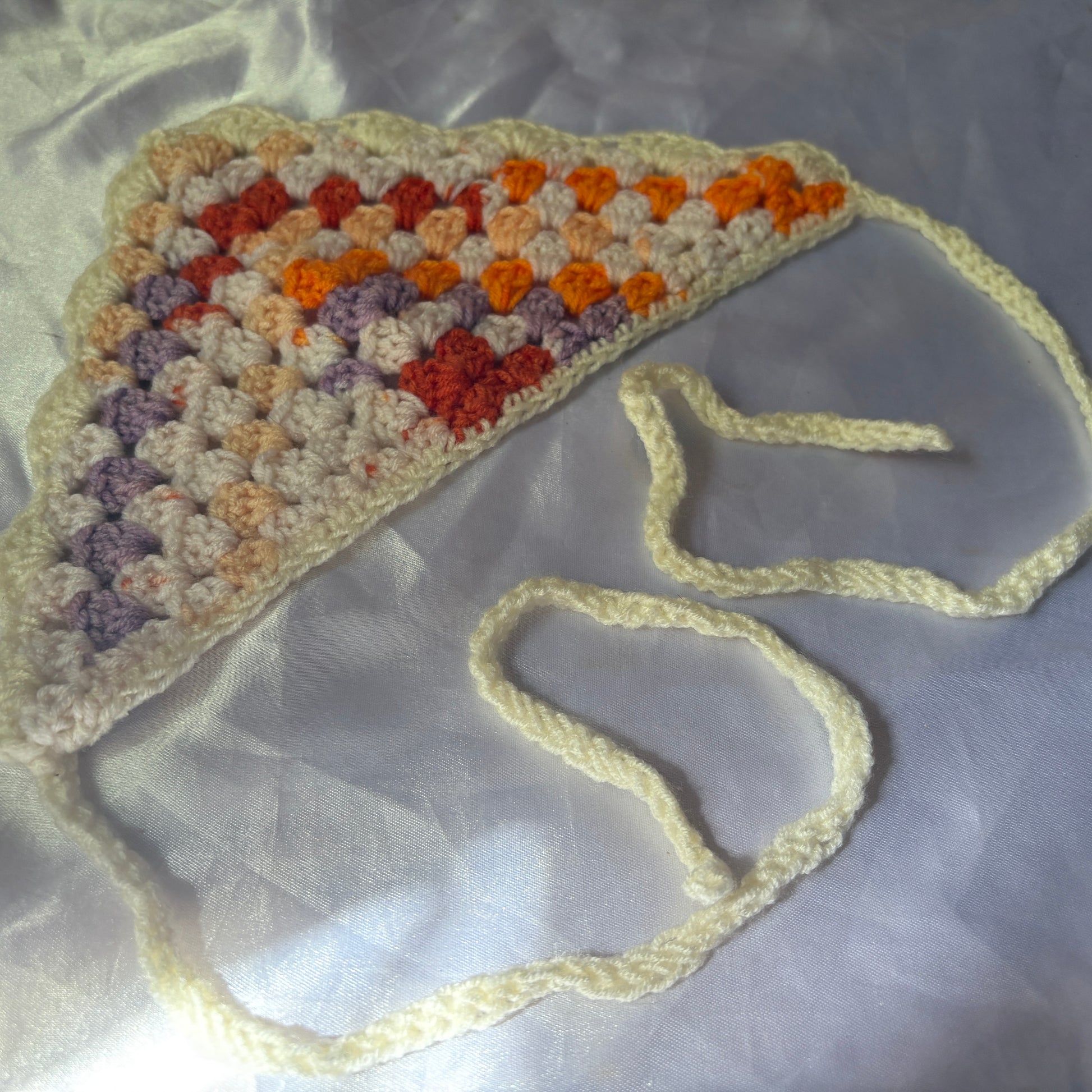 Crocheted bandana with colorful pattern on a reflective surface