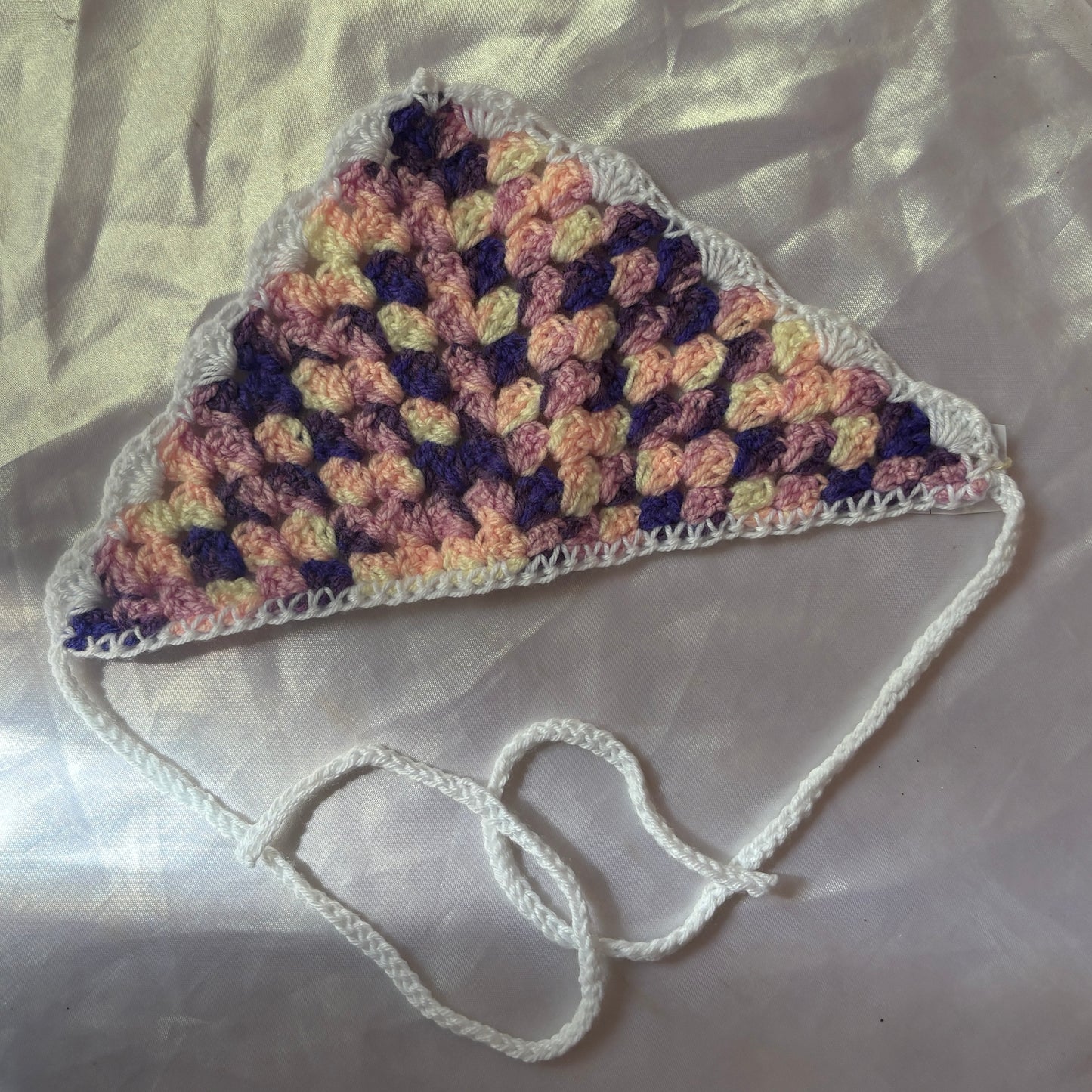 Crocheted bandana with a strap on a light background
