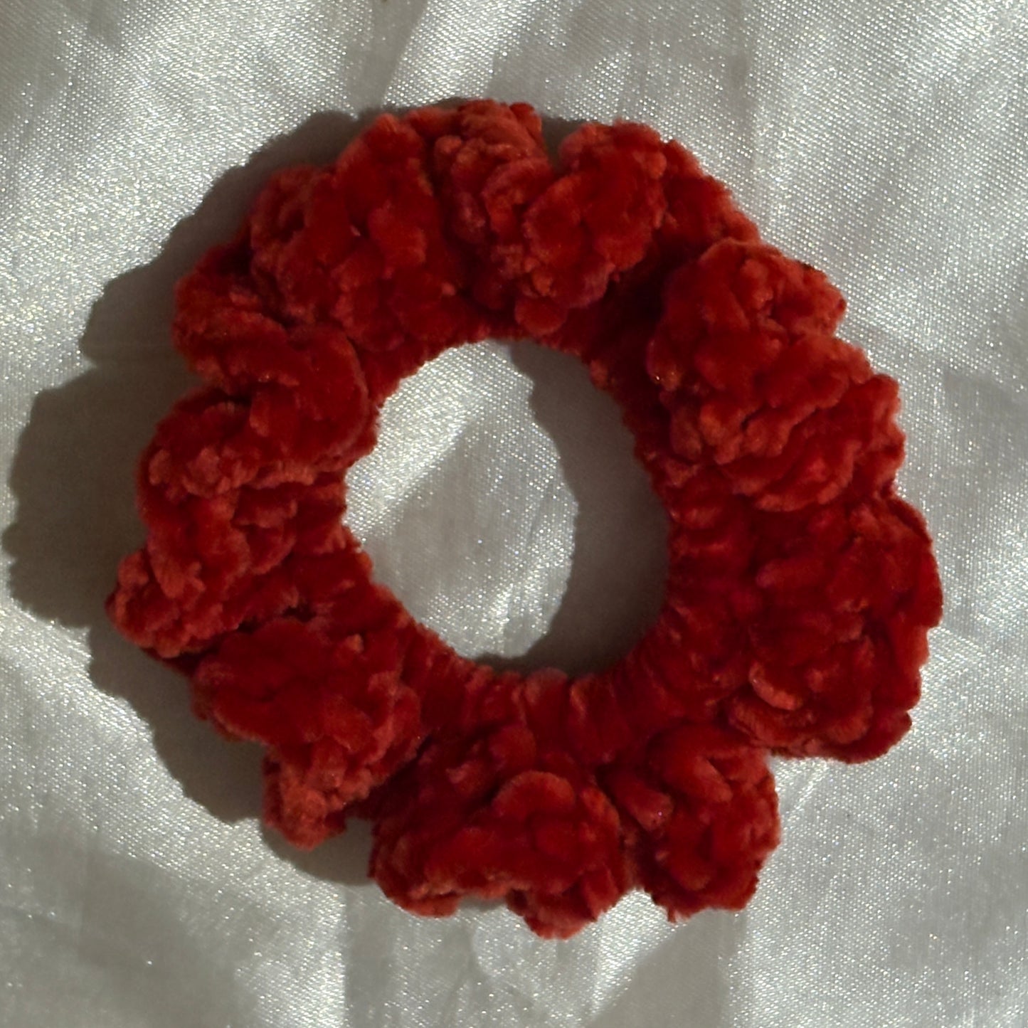Red scrunchie on a white fabric background