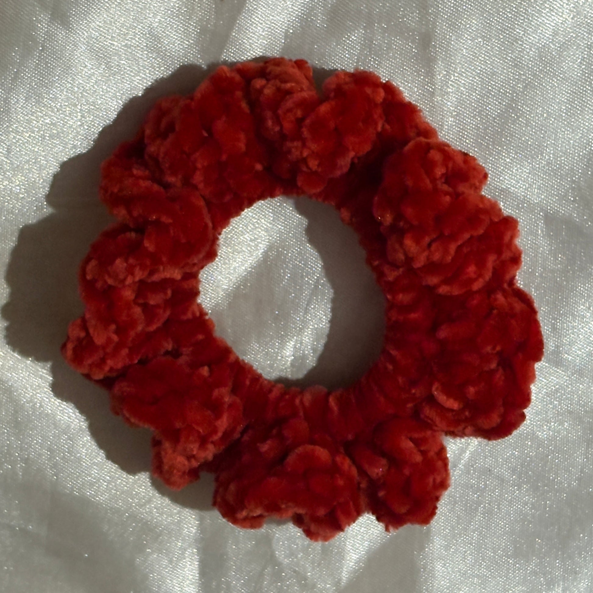 Red scrunchie on a white fabric background