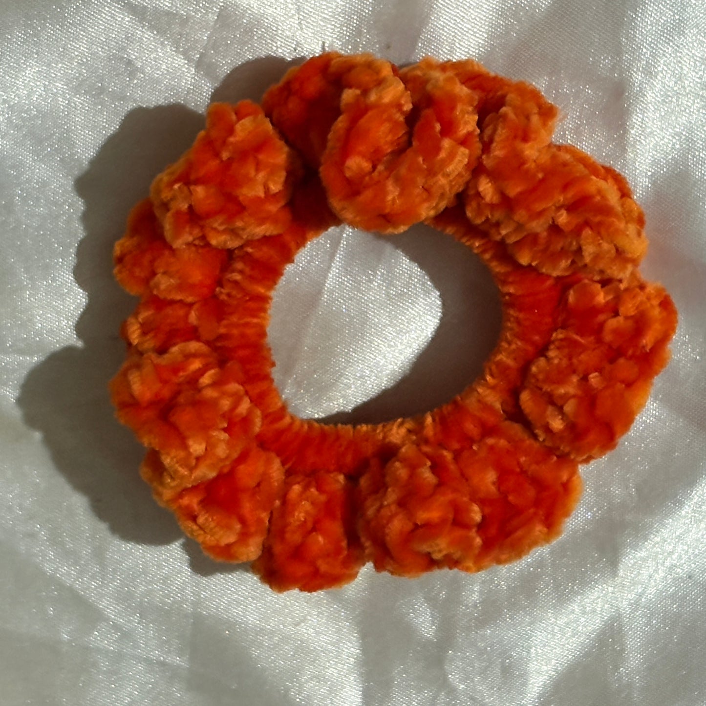 Orange scrunchie on a white fabric background