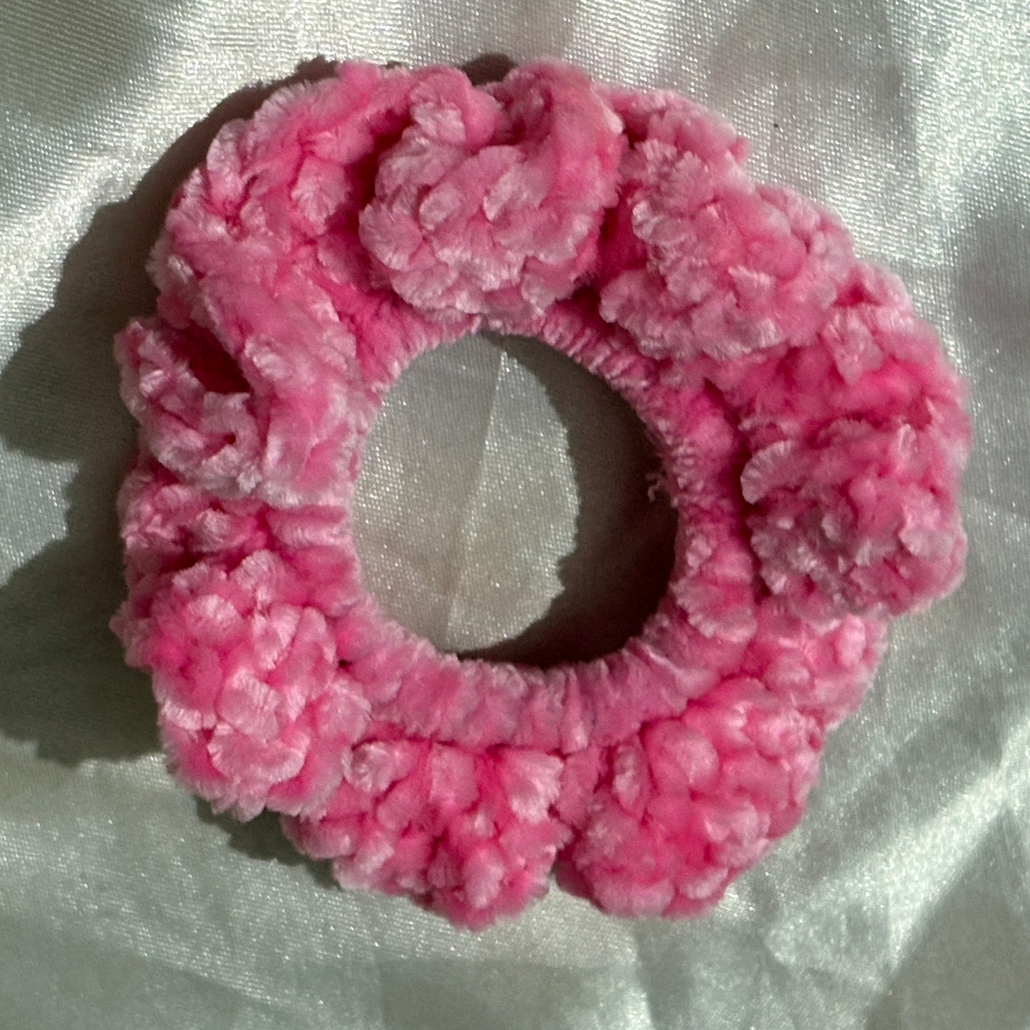 Pink textured scrunchie on a light fabric background
