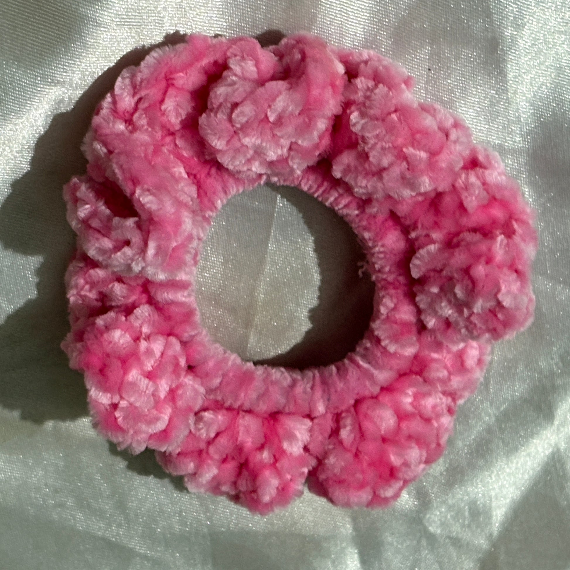Pink textured scrunchie on a light fabric background