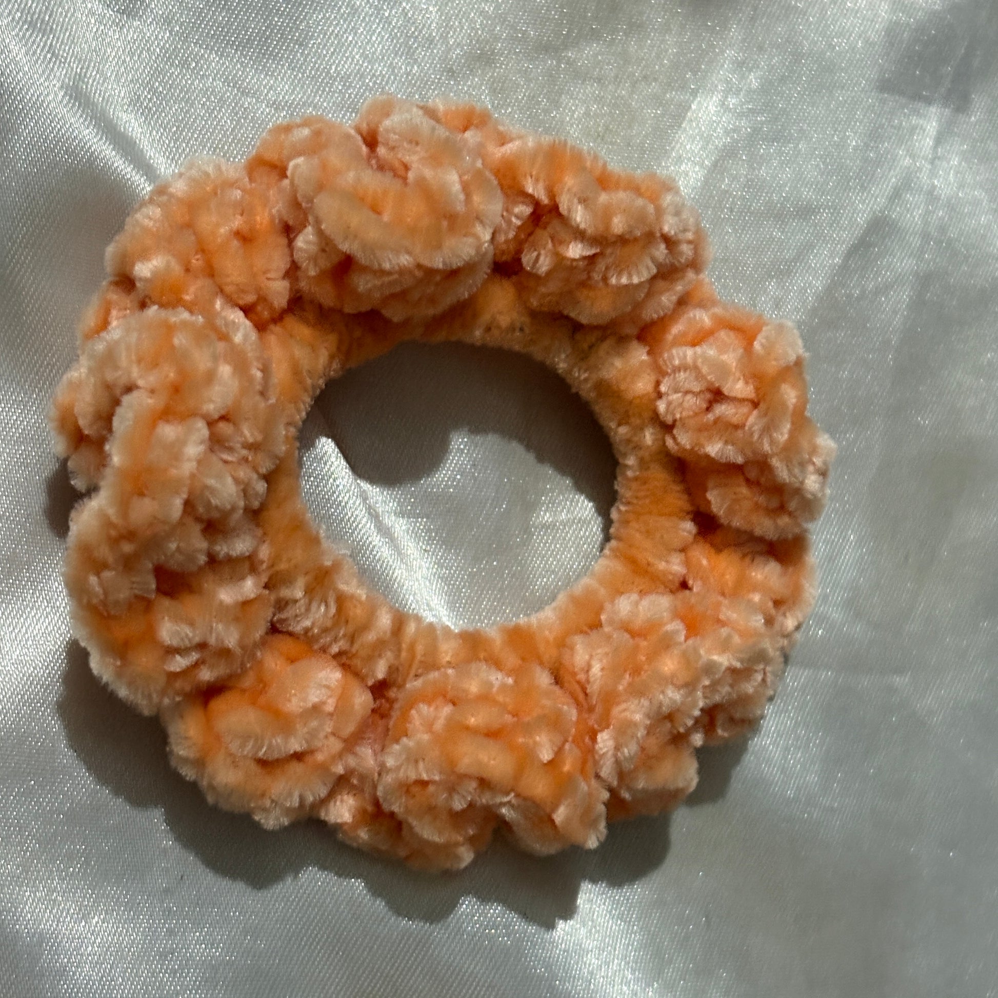 Orange scrunchie on a white fabric background