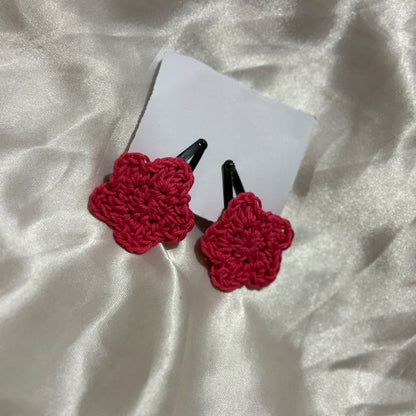 Red crocheted hair clips on a white card with a white fabric background