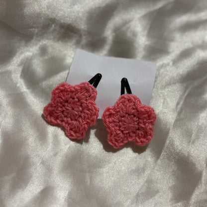 pink crocheted black clips on a white fabric background