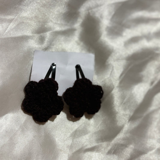  Black crocheted black clips on a white fabric background