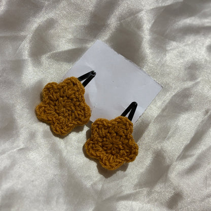 Two brown crochet hair clips on a white fabric background