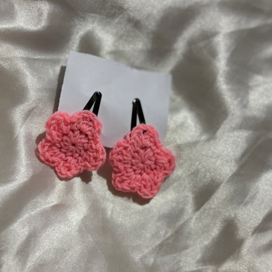 Pink crocheted hair clips on a white card with a light gray background