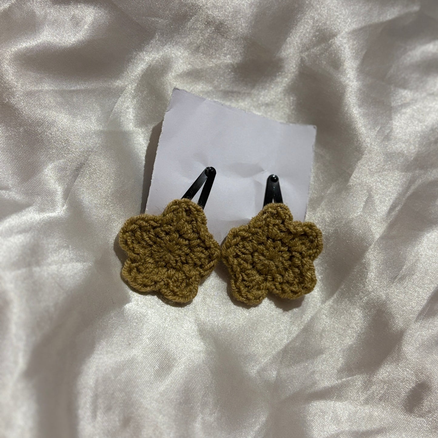 Two tan crochet hair clips on a white fabric background